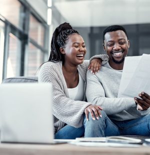 Happy, smiling and carefree black couple checking their finances on a laptop at home. Cheerful husband and wife excited about their financial freedom, savings, investment and future planning.